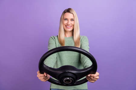 Photo of young beautiful lady learn driver school practicing ride steering-wheel isolated over purple color backgroundの写真素材
