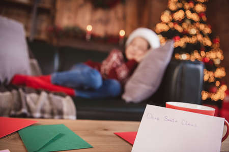 Photo of sleeping charming schoolgirl dressed red sweater headwear closed eyes smiling indoors room...