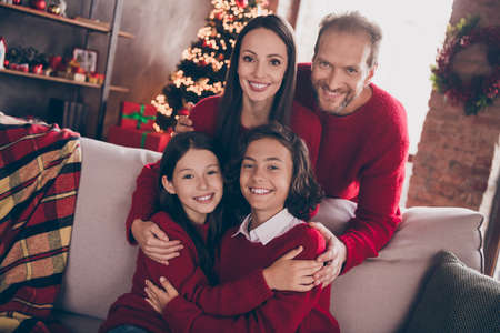 Photo of full family cuddle relax sit on couch wear red jumpers indoors at x-masの写真素材