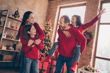 Photo of cheerful nice glad people father carry son piggyback noel party in decorated x-mas home indoorsの写真素材