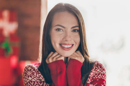 Portrait of attractive cheerful girl spending festal day weekend wearing cozy jumper staying at decorated home indoorsの写真素材