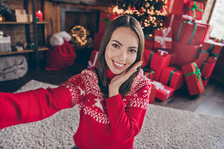 Photo of sweet millennial lady do selfie hand face wear new year sweater at home alone on christmas eveの写真素材