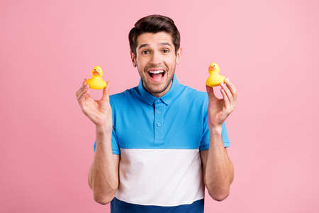 Photo of cool brunet millennial guy hold toy wear blue t-shirt isolated on pink color background