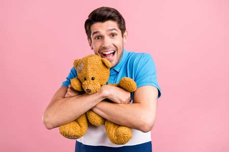 Photo of funky brunet millennial guy hug toy wear striped polo isolated on pink color backgroundの写真素材