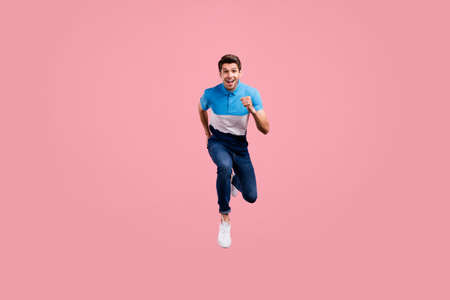 Full body photo of funky brunet young guy run wear polo jeans sneakers isolated on pink background