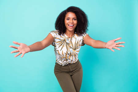Photo of sweet excited dark skin lady wear print t-shirt smiling ready hug you isolated turquoise...
