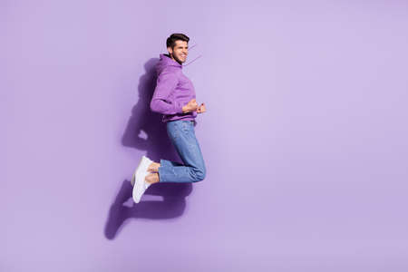Full length body size view of attractive lucky cheerful guy jumping celebrating satisfaction isolated over purple violet color backgroundの写真素材