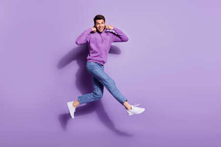Full length body size photo man jumping up wearing hoody isolated pastel purple color backgroundの写真素材