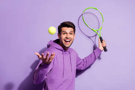 Portrait of attractive cheerful guy playing active tennis having fun isolated over purple violet color backgroundの写真素材