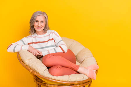 Photo of cute sweet retired woman dressed white sweater smiling sitting chair empty space isolated...