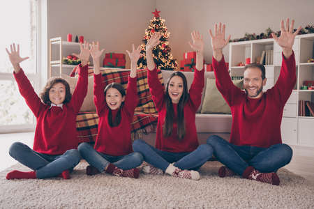 Photo of attractive funny dad mom two children dressed red sweaters rising arms smiling indoors room...