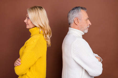 Profile side view portrait of two attractive content grey-haired people folded arms quarrel isolated over brown color backgroundの写真素材