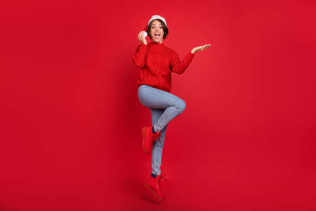 Full size photo of young excited girl happy positive smile hold hand product offer ad isolated over red color backgroundの写真素材