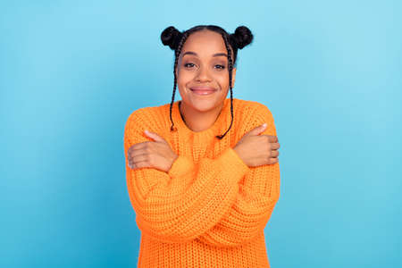 Photo of cool millennial hipster brunette lady hug herself wear orange pullover isolated on blue...