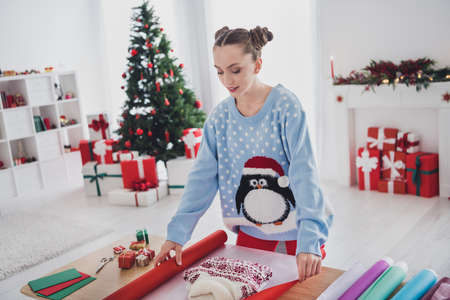 Portrait of attractive focused girl making craft work festal eve day tradition wrapping pullover gift at home indoorsの写真素材