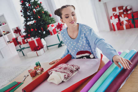 Portrait of attractive cheerful girl making doing craft workshop festal eve tradition wrapping pullover staying at home indoorsの写真素材