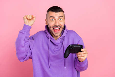Photo of young excited guy rejoice victory lucky race competition videogame isolated over pink color backgroundの写真素材