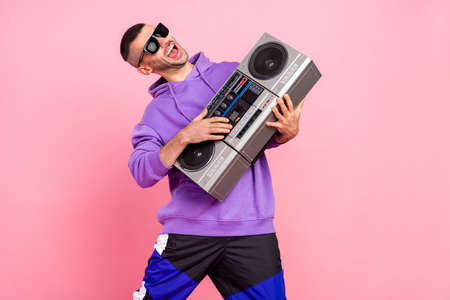 Photo of cool young brunet guy boom box wear eyewear hoodie pants isolated on pink backgroundの写真素材