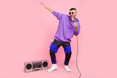 Full body photo of young excited guy street artist sing mic pop music boombox isolated over pink color backgroundの写真素材