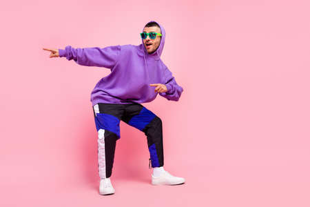Full body photo of cute young brunet guy dance point wear eyewear hoodie pants shoes isolated on pink backgroundの写真素材