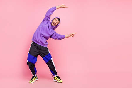 Full length photo of cool young brunet guy point empty space wear hoodie pants shoes isolated on pink backgroundの写真素材