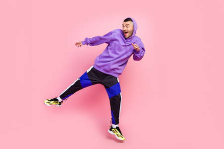 Full length photo of young cheerful guy jump amazed look empty space isolated over pink color backgroundの写真素材
