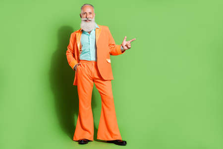 Full length body size view of attractive cheerful man demonstrating copy space isolated over bright green color backgroundの写真素材