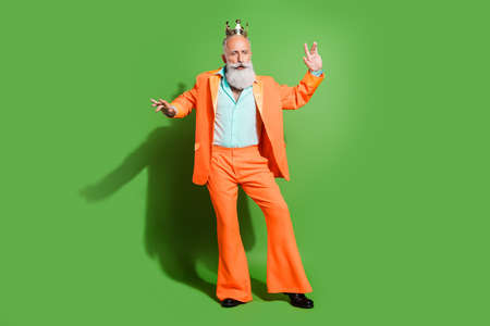 Full length body size view of attractive elegant funky grey-haired man dancing wearing crown isolated over bright green color backgroundの写真素材