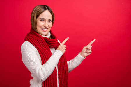 Portrait of attractive cheerful woman demonstrating copy empty space isolated over bright red color backgroundの写真素材
