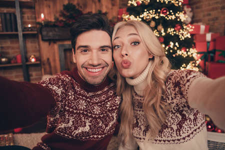 Photo of romantic pretty husband wife dressed pullovers recording noel video congratulations sending kiss indoors room home houseの写真素材