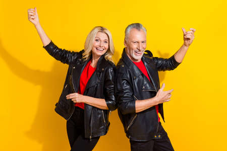 Portrait of attractive cheerful funky pensioner grey-haired lovers dancing fooling good mood isolated over bright yellow color backgroundの写真素材