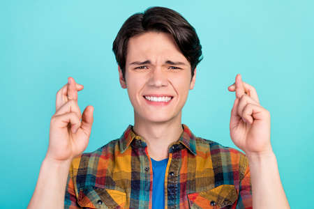 Photo of troubled loser desperate guy crossed fingers wear checkered shirt isolated aquamarine color backgroundの写真素材