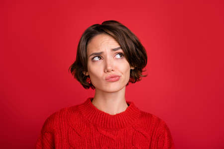 Photo of young woman unhappy sad curious think minded look empty space isolated over red color backgroundの写真素材