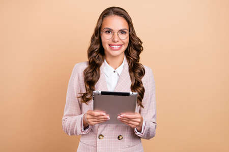 Photo of pretty positive person hold tablet look camera beaming smile isolated on beige color backgroundの写真素材
