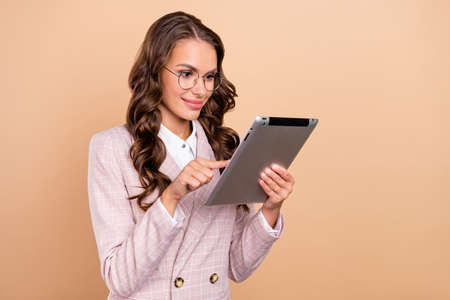 Photo of satisfied pretty lady hold use tablet have good mood coworking networking isolated on beige color backgroundの写真素材