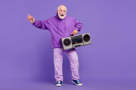 Full length body size view of trendy cheerful man holding boombox having fun isolated over bright violet purple color backgroundの写真素材
