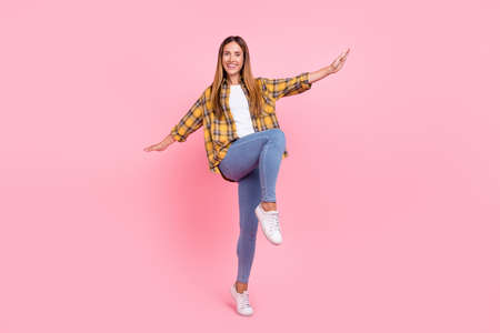 Full length photo of cheerful positive happy young woman raise hands fly plane wings isolated on pink color backgroundの写真素材