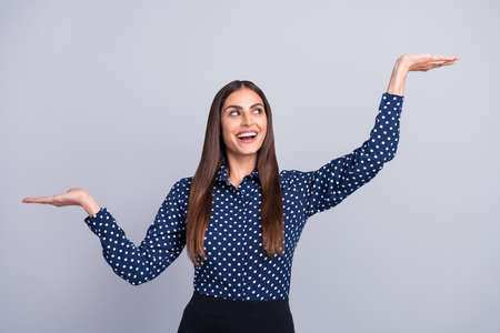 Photo of excited lady hold two hands raise option variant look up wear dotted blouse isolated grey color backgroundの写真素材