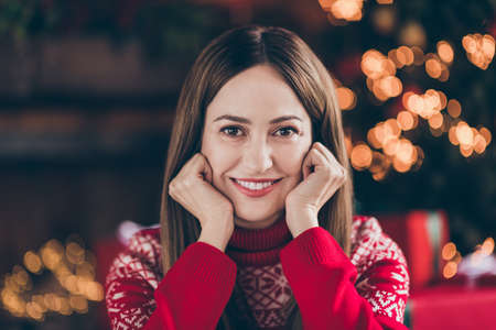 Photo of thoughtful shiny mature lady wear red pullover smiling arms cheeks enjoying christmas indoors house home roomの写真素材