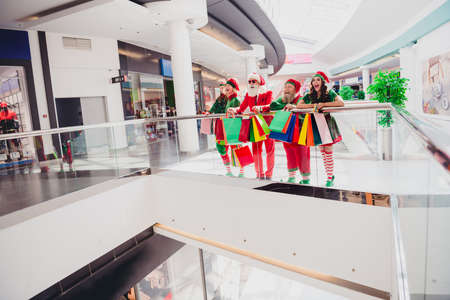 Full length body size view of attractive company elfs buying festal gifts eve occasion surprise at big shopping mall indoorsの写真素材
