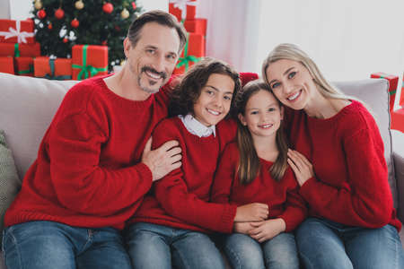 Portrait of careful big full affectionate cheerful family wife husband brother sister sitting on sofa mommy daddy cuddling at home indoorsの写真素材
