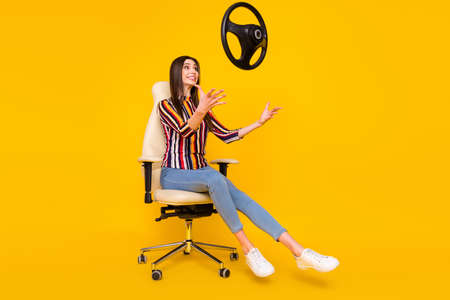 Full length profile side photo of young woman happy positive smile catch steering-wheel isolated over yellow color backgroundの写真素材
