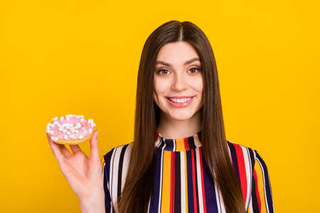 Photo of young girl happy positive smile hold doughnut tasty delicious sugar calories isolated over yellow color backgroundの写真素材