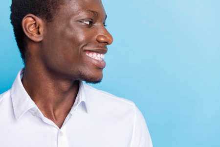 Photo of charming sweet dark skin guy dressed formal shirt smiling looking empty space isolated blue color backgroundの写真素材