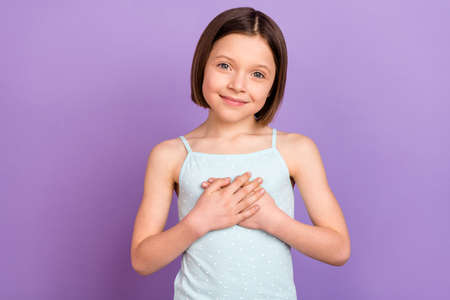 Photo of positive happy young little girl hold hands heart pledge isolated on pastel purple color backgroundの写真素材