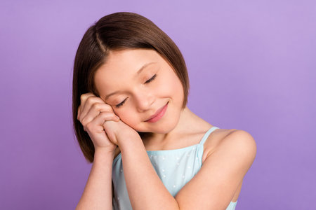 Photo of cute brown hairdo small girl sleepy wear blue top isolated on violet color backgroundの写真素材