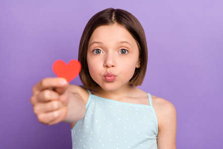 Photo of cheerful young small girl give little red paper heart shape you isolated on violet purple color backgroundの写真素材