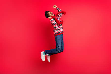 Full size photo of young afro guy happy positive smile jump celebrate victory lucky isolated over red color backgroundの写真素材