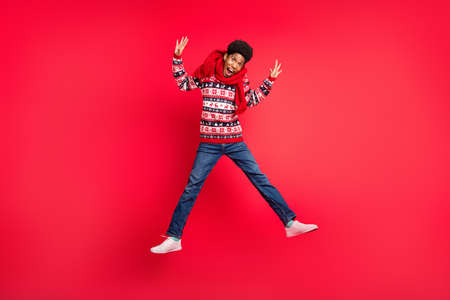 Full length photo of millennial brunet guy jump wear holiday scarf sweater jeans shoes isolated on red backgroundの写真素材