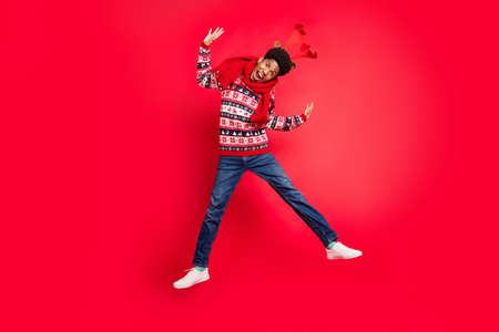 Full size photo of young brunet guy jump wear holiday scarf sweater jeans shoes isolated on red backgroundの写真素材